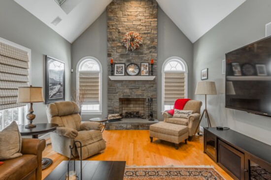 The family room in the home has a floor-to ceiling fieldstone fireplace and wood floors. 